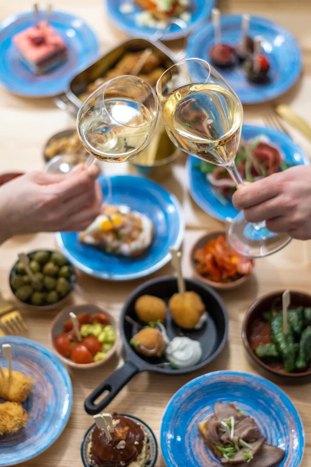 Tapas shora, dva hosté si přiťukávají vínem