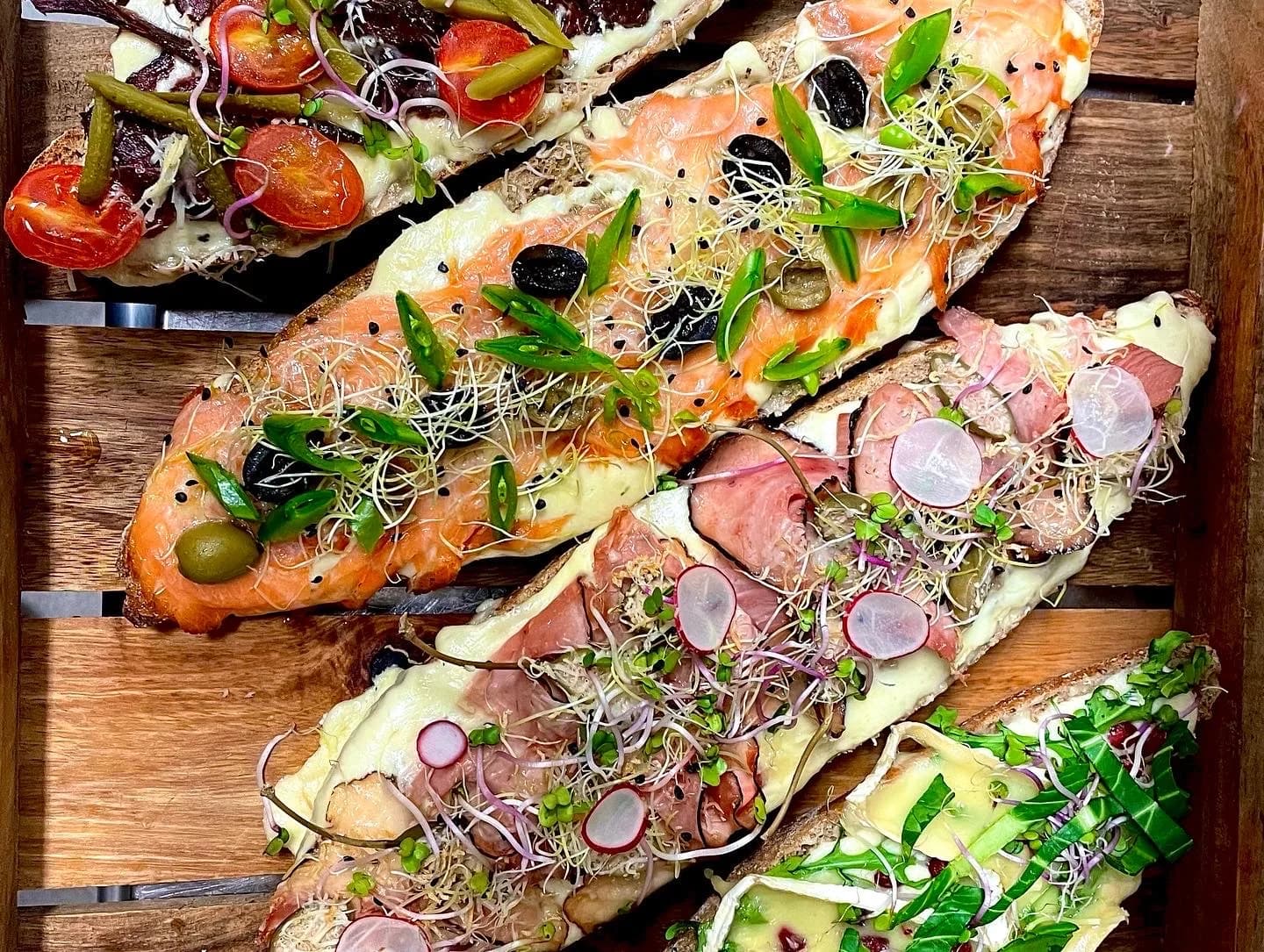 Rozpečené bagety pintxos s lososem a šunkou na prkně